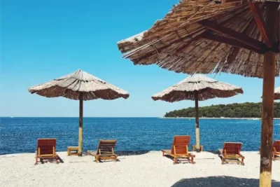 Einige Liegen und Sonnenschirme am Beach Porton Biondi Nahe Rovinj.