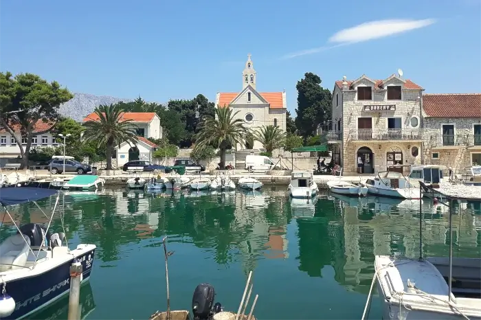 Hafen von Sućuraj mit Booten und umliegenden Küstengebäuden.