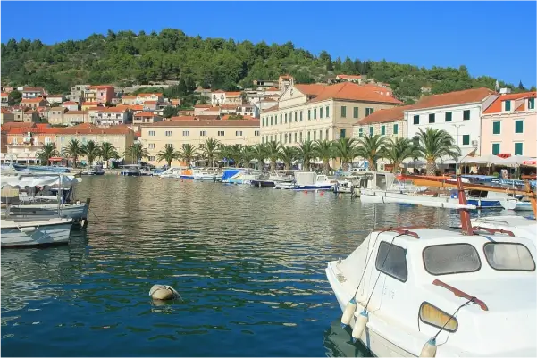 Panoramablick auf die Stadt Vela Luka, Kroatien, mit Blick auf das Meer, Boote und umliegende Hügel.