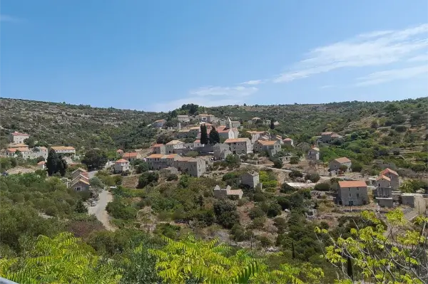 Blick auf das Dorf Velo Grablje mit Steinhäusern und mediterraner Vegetation.