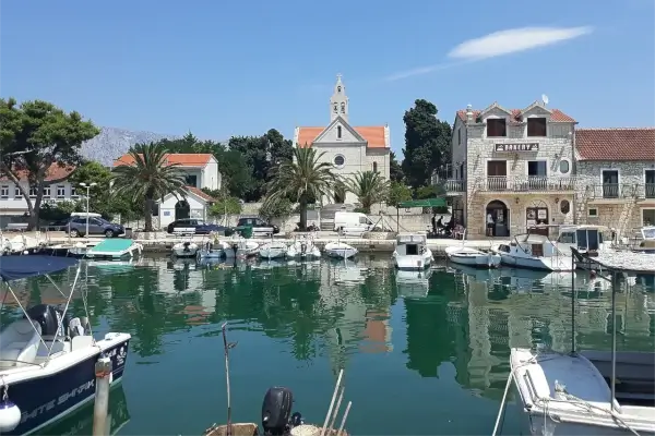 Hafen von Sućuraj mit Booten und umliegenden Küstengebäuden.