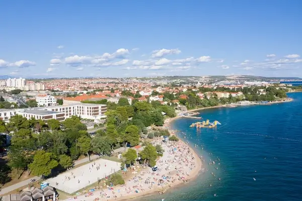 Ansicht des Strandes Kolovare an der Adriaküste von Zadar mit klarem Wasser und Kieselstrand.