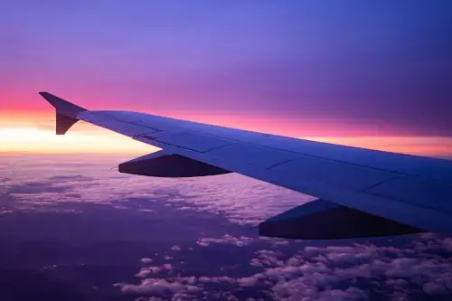 Flugreise, Anreise mit dem Flugzeug, Blick aus dem Flugzeug auf den Sonnenuntergang.