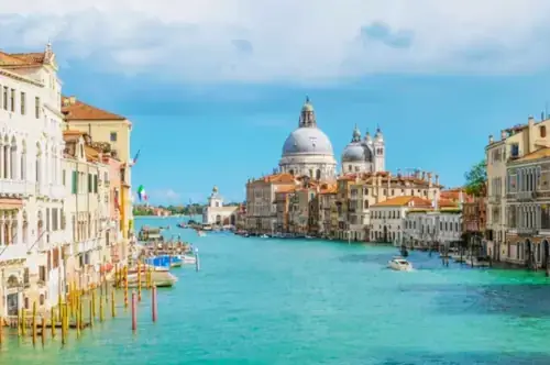 Blick auf den Canal Grande von Venedig mit der Kuppel der Santa Maria della Salute an einem sonnigen Tag.