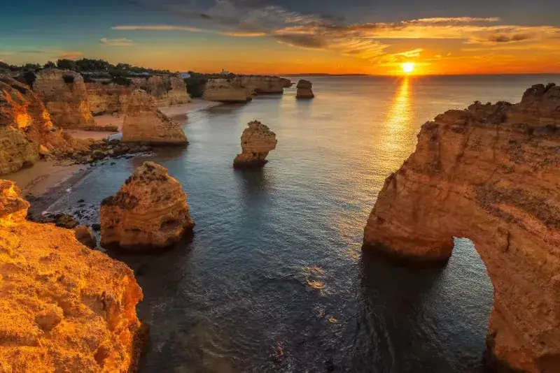 Sonnenuntergang über den Felsen und Buchten am Praia da Marinha, Algarve, Portugal.
