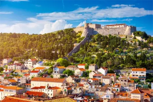 Blick auf die Häuser der Stadt Hvar mit der Festung Fortica (Španjola) auf dem Hügel im Hintergrund.