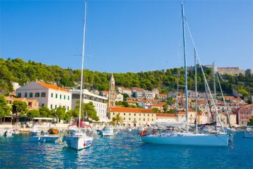 Panoramablick auf die Stadt Hvar mit der Festung im Hintergrund, umrahmt von Booten im Hafen.