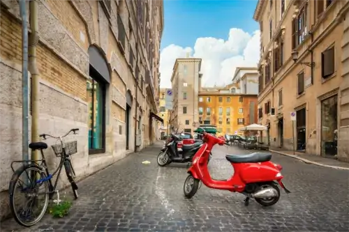 Rote Vespa in einer ruhigen Straße in Rom, Italien