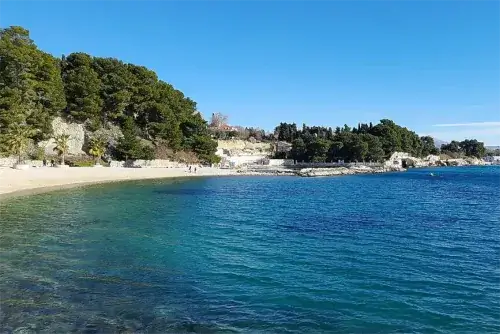Malerischer Blick auf den Ježinac Strand in Split mit klarem Wasser und felsiger Küstenlinie.